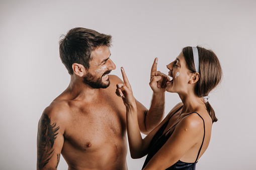 Playful couple applying facial skin creme to each other.