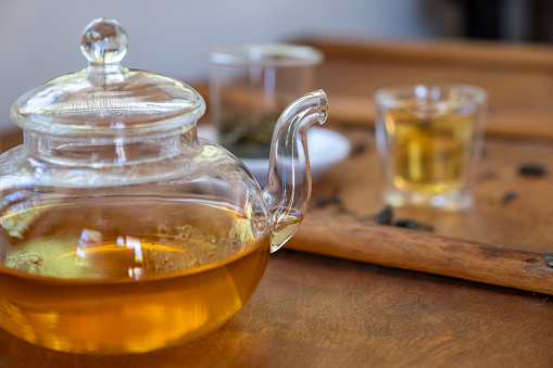 Studio shot of a cup of tea and some loose tea leaves on a wooden counter top