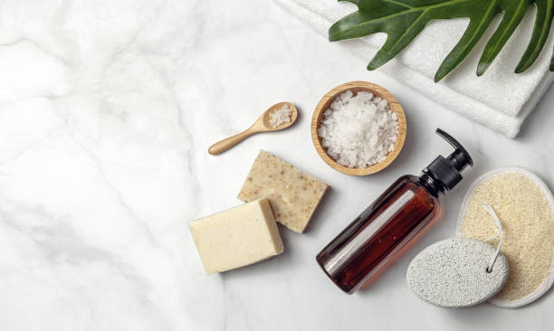 istock Amber glass cosmetic bottle with spa element and towel with green leaf on marble background. 1299041515