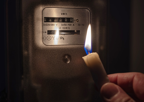 El medidor de electricidad está iluminado por la luz de una vela. Apagón, concepto de apagón. photo
