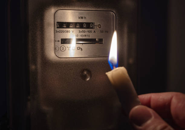 The electricity meter is illuminated by the light of a candle. Power outage, blackout concept. stock photo
