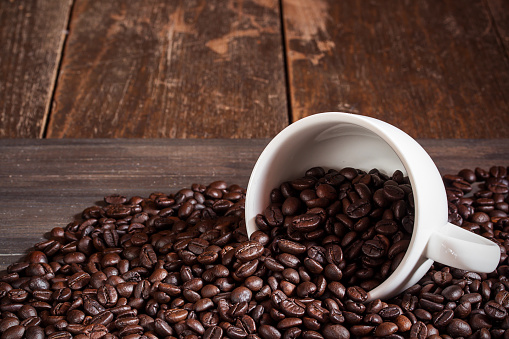 Coffee cup and coffee beans on dark wooden table