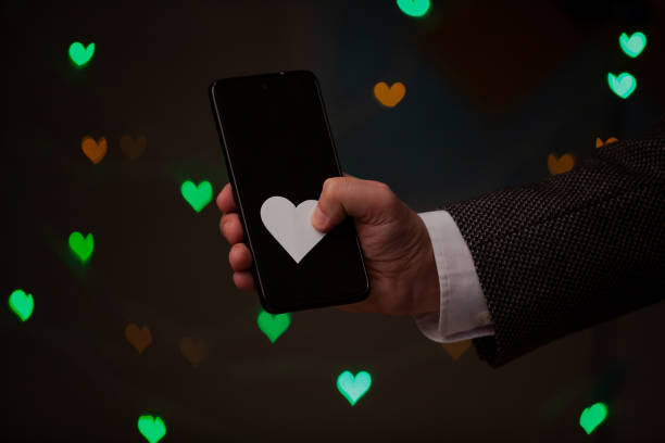 istock Man hand holds phone and paper heart 1299044928