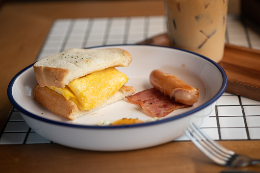 Egg in sandwich, sausage and bacon served with iced coffee. Morning healthy breakfast