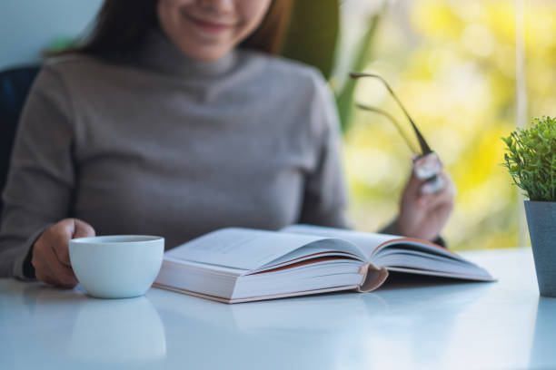 istock a beautiful young asian woman holding eye glasses while reading book 1299051344