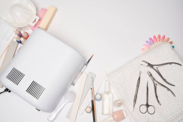 istock manicure and pedicure items - nail polish drying lamp, nail file, scissors and brushes over light background 1299051440