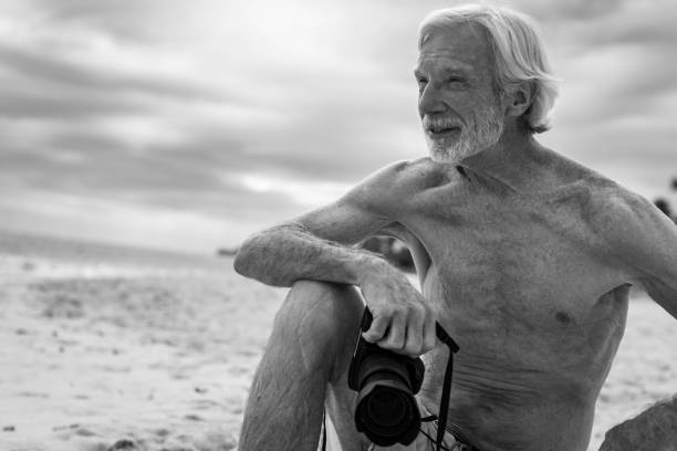 istock Old senior handsome active man sitting outdoor holding a camera. Retirement and leisure. 1299051610