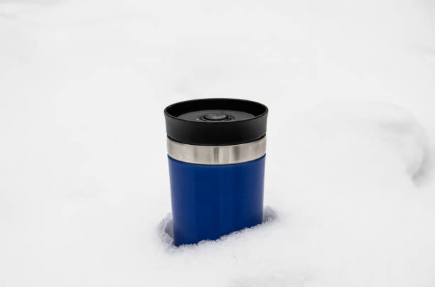 istock blue thermocup with hot tea on white snow 1299051831