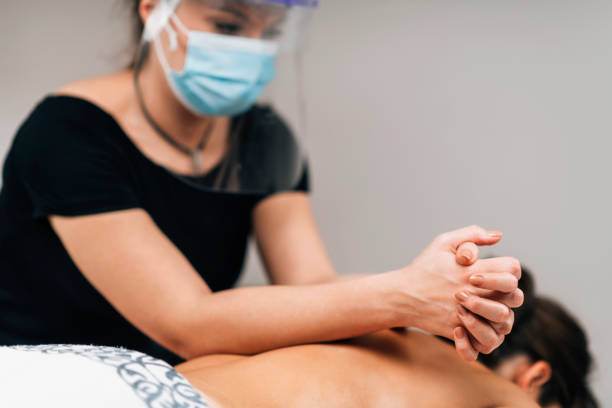 istock Lomilomi Practitioner wearing a Protective Mask, Giving Back Massage at a Wellness Center 1299055256