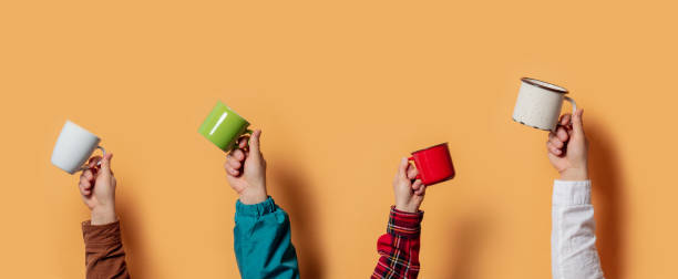 istock Four male hands holding cups with coffee or tea on yellow background 1299056272