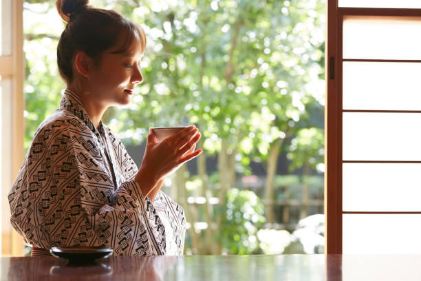 eine junge asiatin entspannt sich im japanischen traditionsgasthof - japanese tea cup stock-fotos und bilder