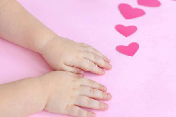 istock Children's hands on a pink background with hearts. 1299059994