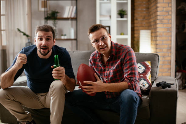 istock Men drinking beer and watching sports game on tv. 1299060074