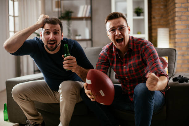 istock Men drinking beer and watching sports game on tv. 1299060826