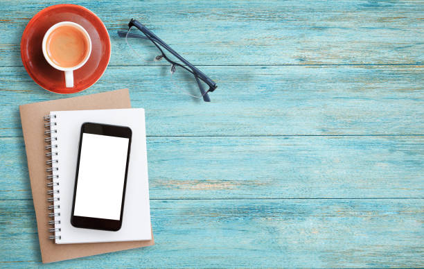 istock Cup of coffee, smart phone and notebook on a wood table background. 1299062597