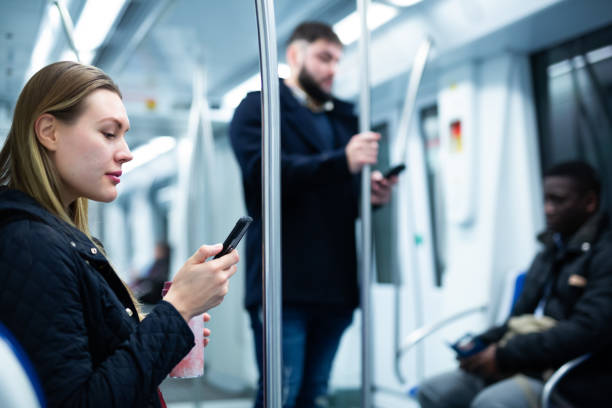 istock Young woman browsing on phone in metro car 1299062851