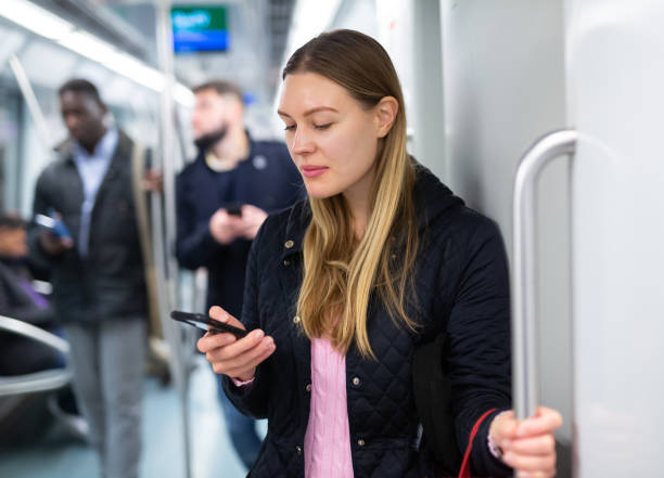 istock Young woman browsing on phone in metro car 1299062877