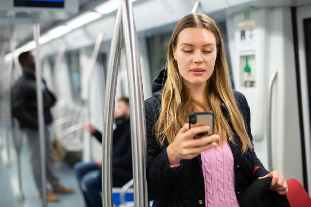 istock Young woman with phone in subway car 1299062886