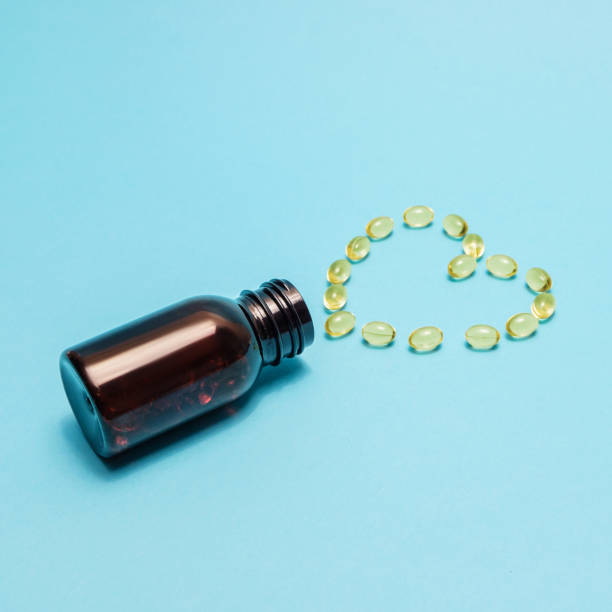 istock Fish oil capsules in heart shape on a blue background. 1299063873