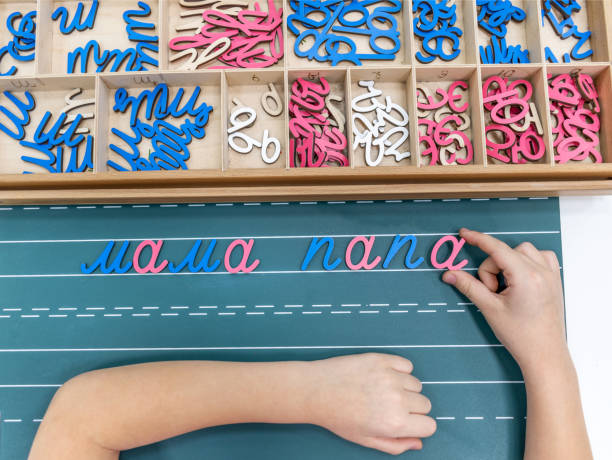 top-ansicht von kindern hände bauen von wörtern mit farbigen montessori bewegliche alphabet aus dem holztablett auf der tafel. - reading and writing classroom alphabet learning stock-fotos und bilder