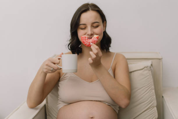istock Pregnant woman enjoying donuts and tea. 1299065552
