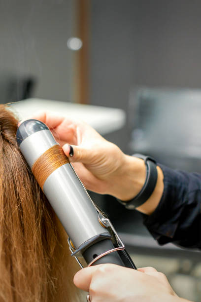 istock Hairdresser makes curls with curling iron 1299066379
