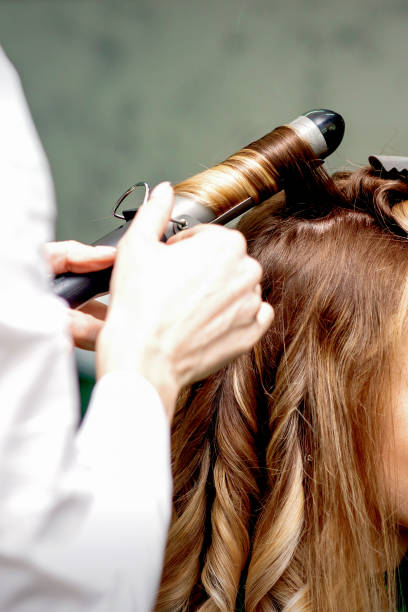 istock Hairdresser makes curls with curling iron 1299066559