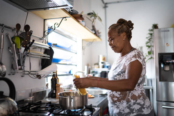 mujer mayor cocinando pasta en casa - padres-amos-de-casa-ilustraciones fotografías e imágenes de stock