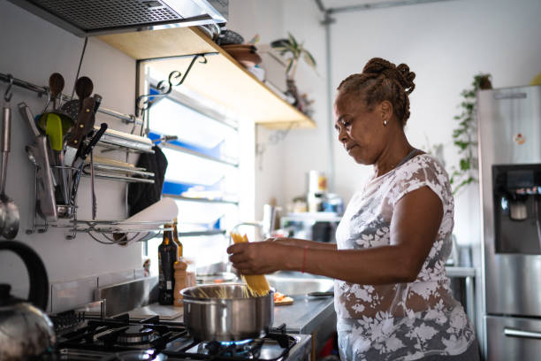 mulher sênior cozinhando macarrão em casa - mãe dona de casa - fotografias e filmes do acervo
