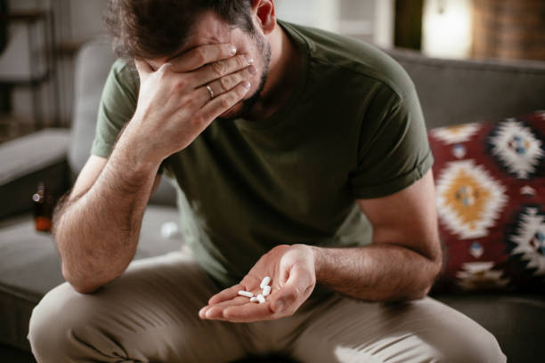 sad unhappy depressed man is holding a pill in a hand. - narcotic medicine pill insomnia imagens e fotografias de stock