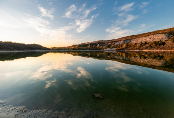 Beautiful autumn landscape with blue sky and clouds reflected in the lake