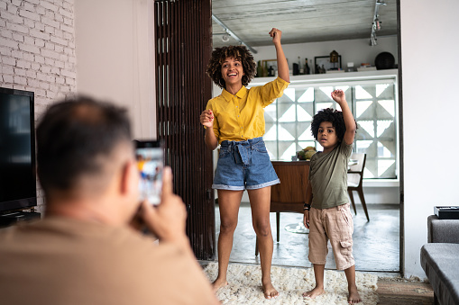 Father filming on smartphone family dancing at home