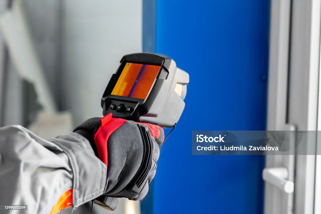 Thermal imaging. A thermal imager in the hands of an electrician conducting an inspection of the equipment Thermal Image Stock Photo