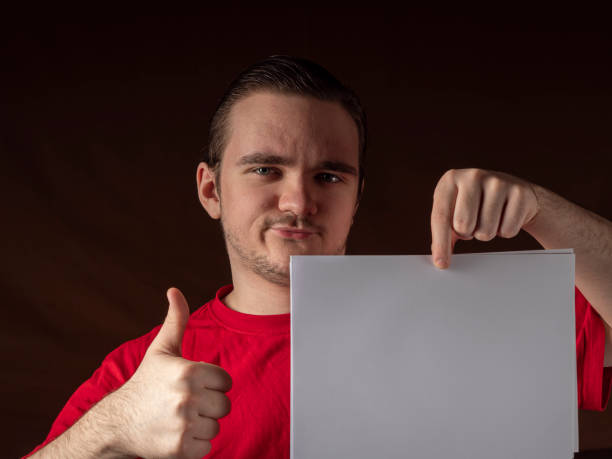 istock Young guy in a red t-shirt looks at camera 1299072272