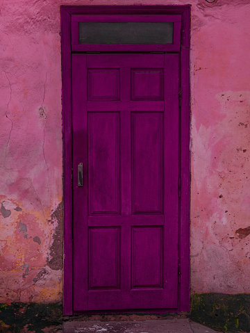 Vintage purple wooden door. Antique building exterior detail. Street photo. Retro violet wood boards. Empty abstract grunge painted texture, colorful weathered wall.