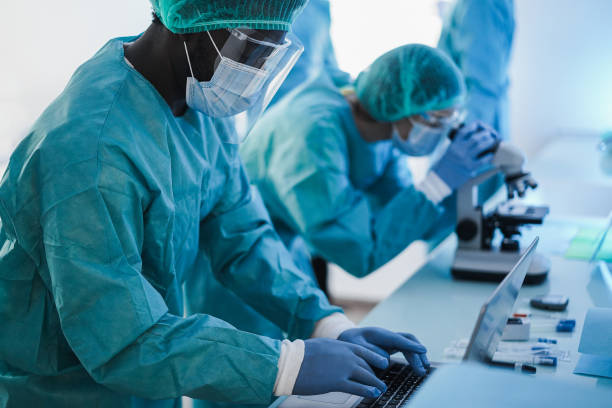 istock Medical workers in hazmat suit working with laptop computer and micoroscope inside laboratory hospital during coronavirus outbreak 1299074728