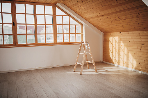 Empty room with a ladder in the middle of it, no people.