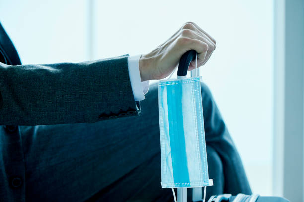 istock man with a suitcase and a disposable face mask 1299076431