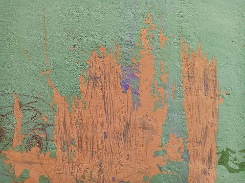 The green walls are streaked with orange paint. Rough and abstract textured walls.