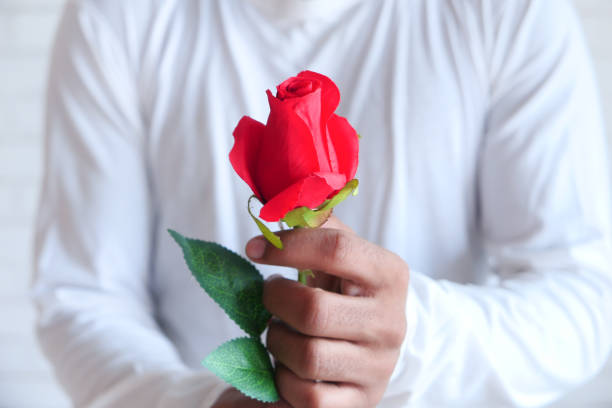 istock unrecognized man hand holding rose flower on white background 1299076519