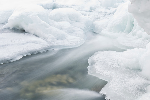 Shelf ice with flowing water in winter in Northern Norway. The water is blurred caused by a slow shutter speed.