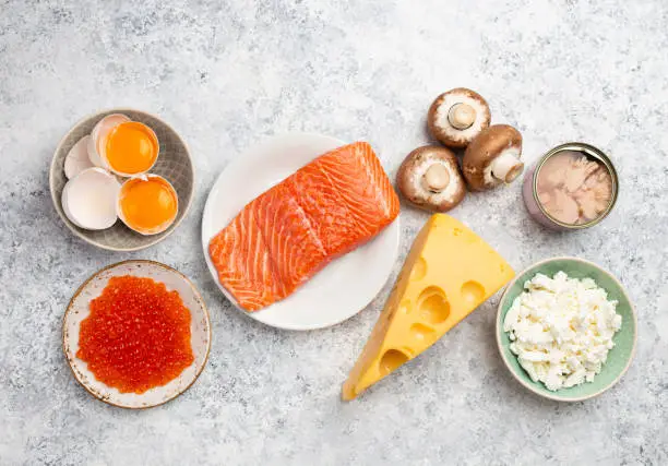 Selection of natural sources of vitamin D: fresh salmon, caviar, cheese, mushrooms, tuna, eggs on white stone background top view. Assorted foods and products rich in vitamin D, from above
