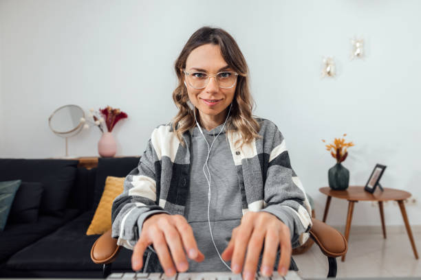 jeune femme travaillant à la maison avec l’ordinateur regardant l’appareil-photo. - looking at camera smiling desk isolated photos et images de collection