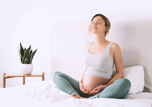 mujer embarazada en pose de loto haciendo meditación o ejercicios de respiración para un embarazo saludable y preparando el cuerpo para el parto. - human pregnancy yoga exercising prenatal care fotografías e imágenes de stock