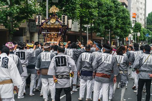 Shinjuku, Tokyo, Japan - 26/05/2018: Crowds of japanese people carrying Shinto Shrine Mikoshi on their shoulders around the neighborhood during the Matsuri.