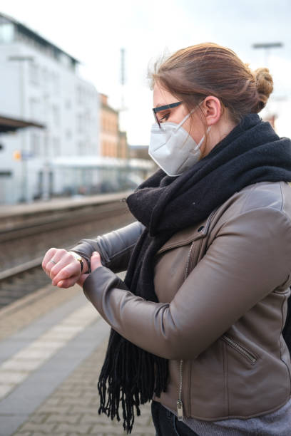 istock Young adult checking the time on the train station wearing protective mask 1299085392