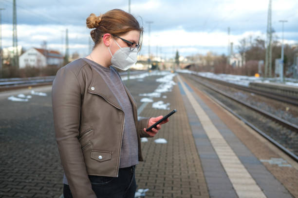 Young adult waiting on the train station wearing protective mask