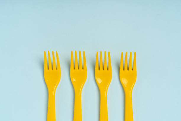 istock Yellow plastic disposable forks arranged in a row on a blue background, minimalism. The concept of pollution of the environment 1299086757