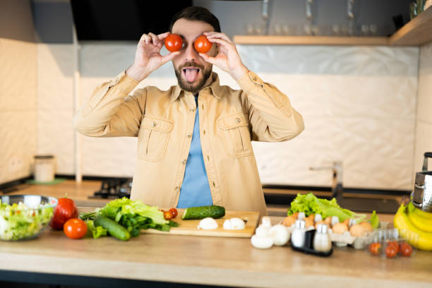 istock White man with beard is smiling and having fun in kitchen. Happy vegan man is cooking salad using only nutrition and healthy food 1299087853
