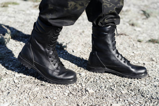 istock Man in black army boots with laces and khaki pants 1299088091